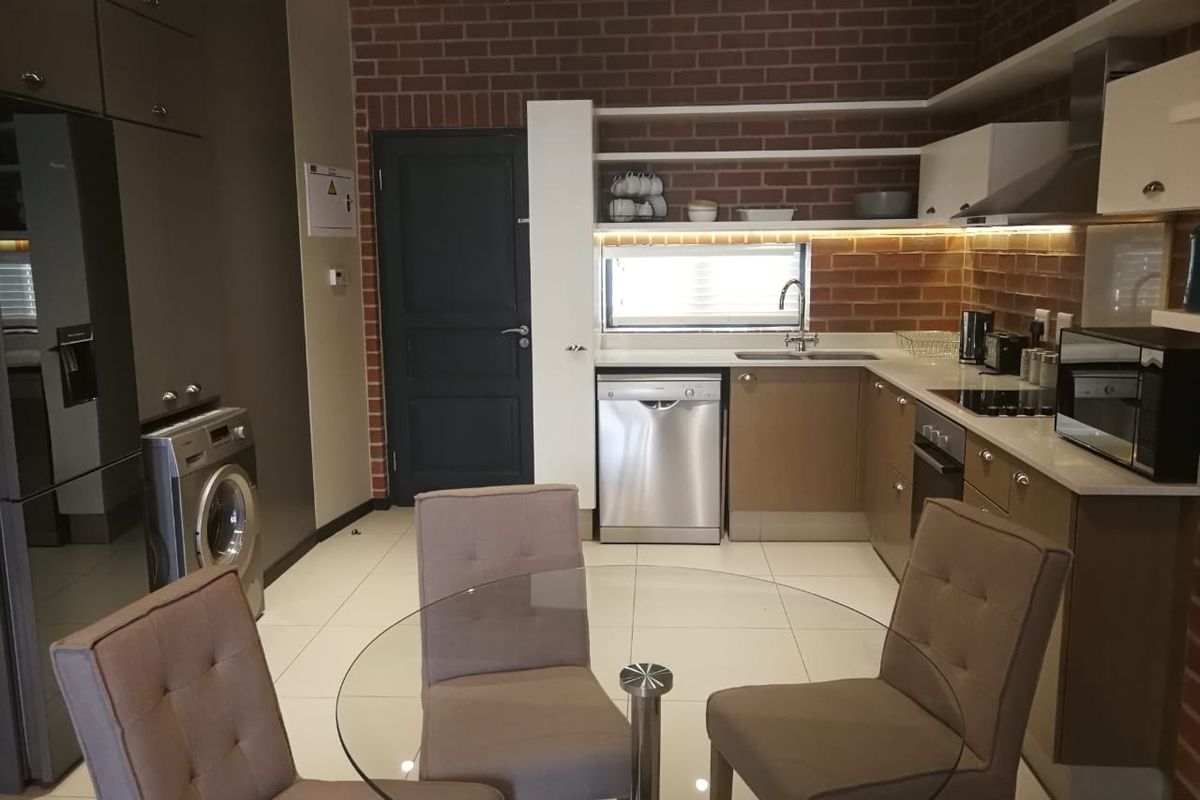 Modern kitchen featuring exposed brick walls, sleek cabinetry, integrated appliances, and under-cabinet lighting, creating a stylish and functional culinary space.