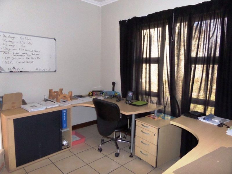 A functional home office space featuring tiled flooring and a large window, providing a practical area for work or study.