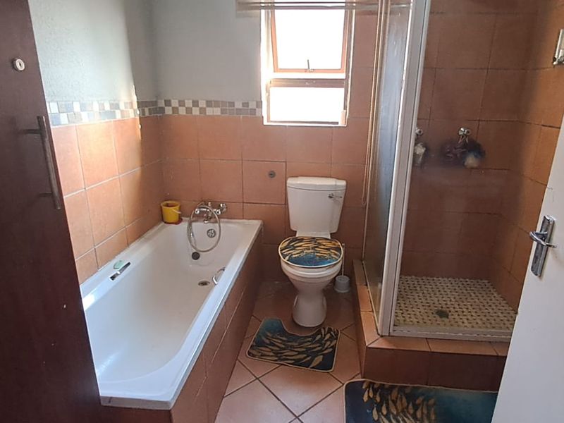 A dated bathroom featuring a bathtub, separate shower enclosure, and toilet with tiled finishes throughout.