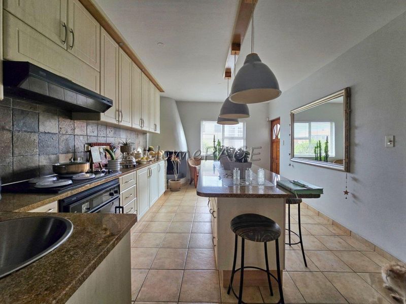 Spacious kitchen featuring granite countertops, ample built-in cabinetry, a central island, and a unique fireplace, creating a warm and functional culinary space.