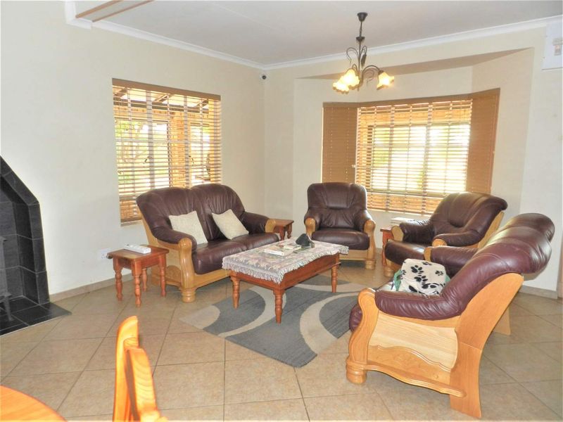 A spacious living room featuring tiled flooring, a built-in fireplace, and a bay window that provides ample natural light.