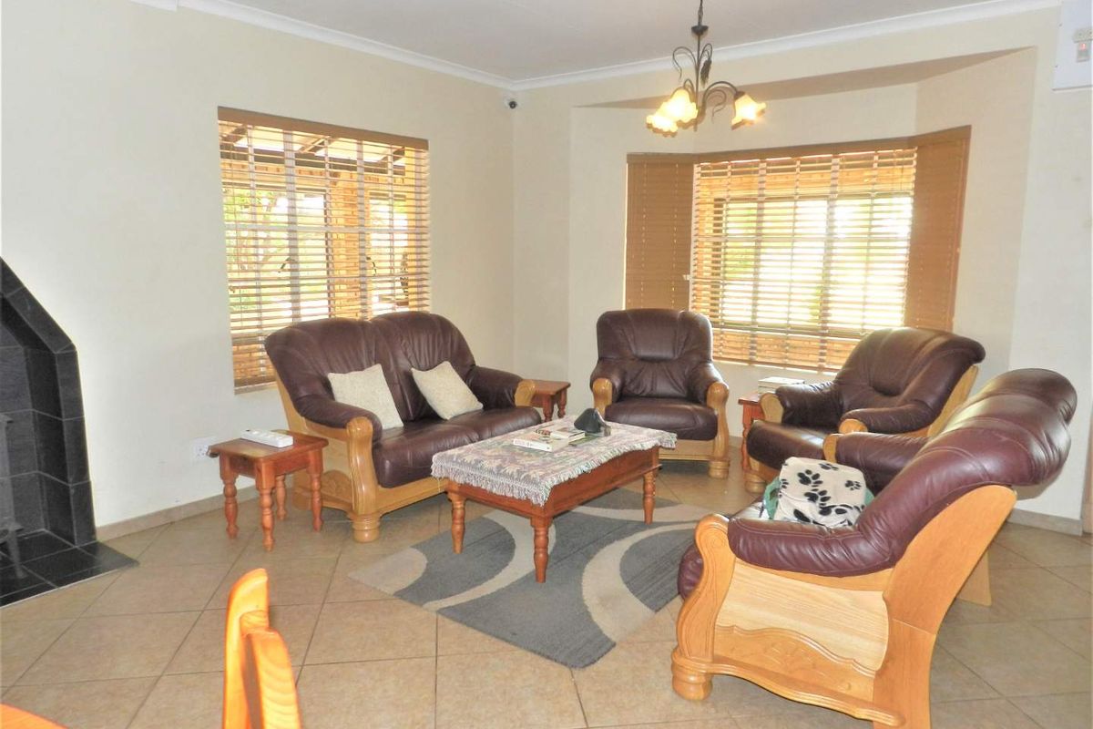 A spacious living room featuring tiled flooring, a built-in fireplace, and a bay window that provides ample natural light.