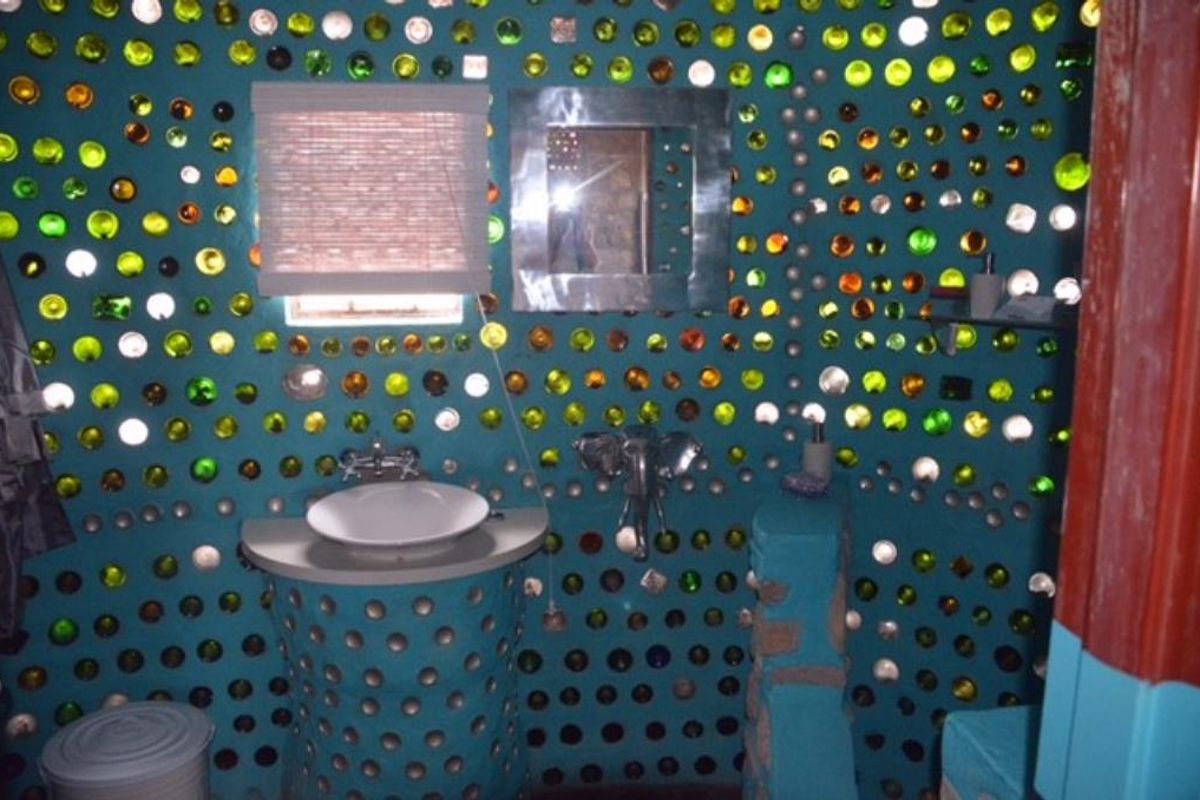 Unique bathroom featuring custom walls constructed from embedded glass bottles, a vessel sink, and a built-in vanity base.
