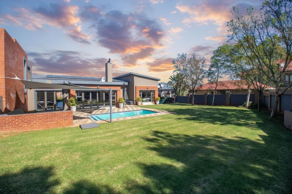 Spacious rear garden featuring a swimming pool, paved patio area, and well-maintained lawn, complemented by a modern brick and rendered facade.