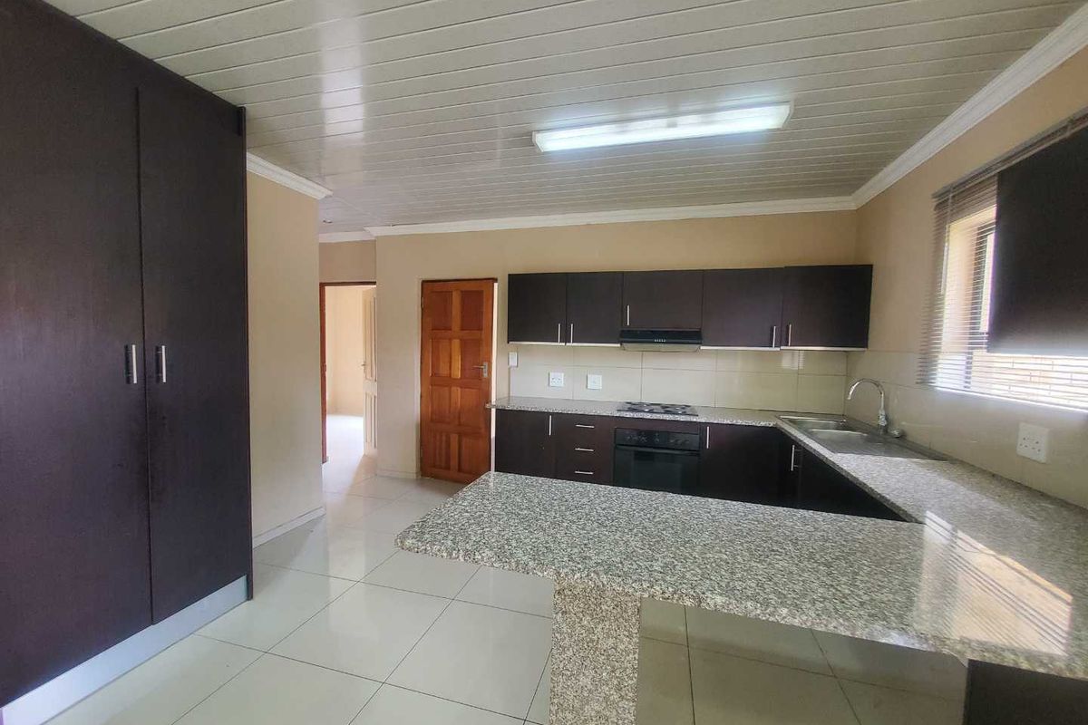 A functional kitchen featuring dark cabinetry, granite countertops, a built-in oven and hob, and tiled flooring.
