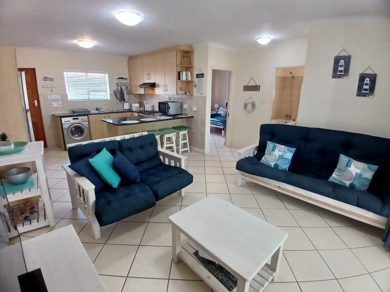 Open plan living area featuring a functional kitchen with built-in cabinetry, tiled flooring, and direct access to adjacent rooms.
