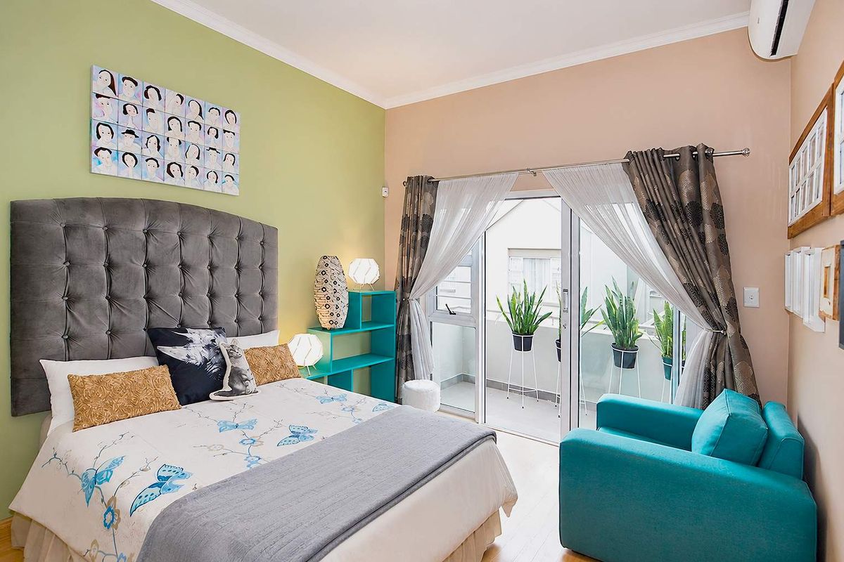 A well-maintained bedroom featuring laminate flooring, an air conditioning unit, and a sliding glass door providing access to a private balcony.