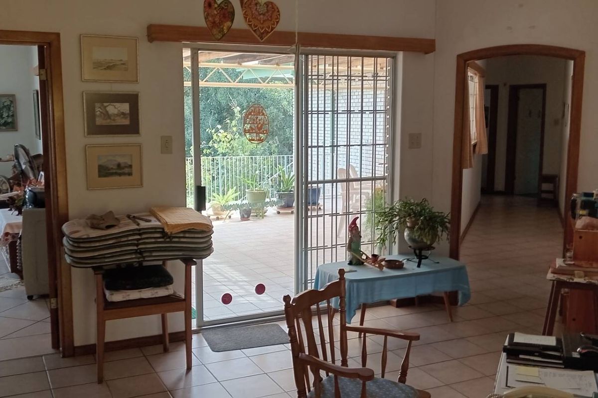 A living area featuring tiled flooring, wooden door frames, and a sliding glass door leading to an outdoor patio space.