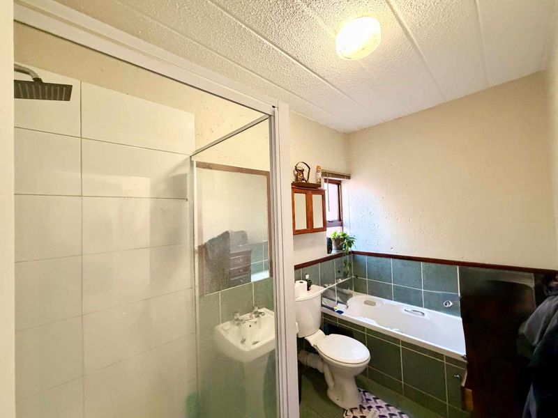 A functional bathroom featuring a separate shower enclosure, bathtub, pedestal basin, and toilet with dated tile finishes.