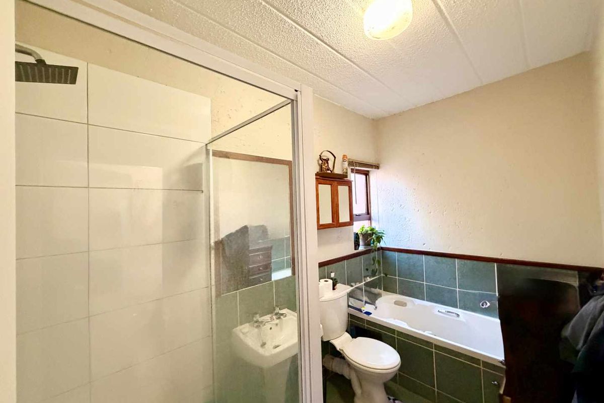 A functional bathroom featuring a separate shower enclosure, bathtub, pedestal basin, and toilet with dated tile finishes.