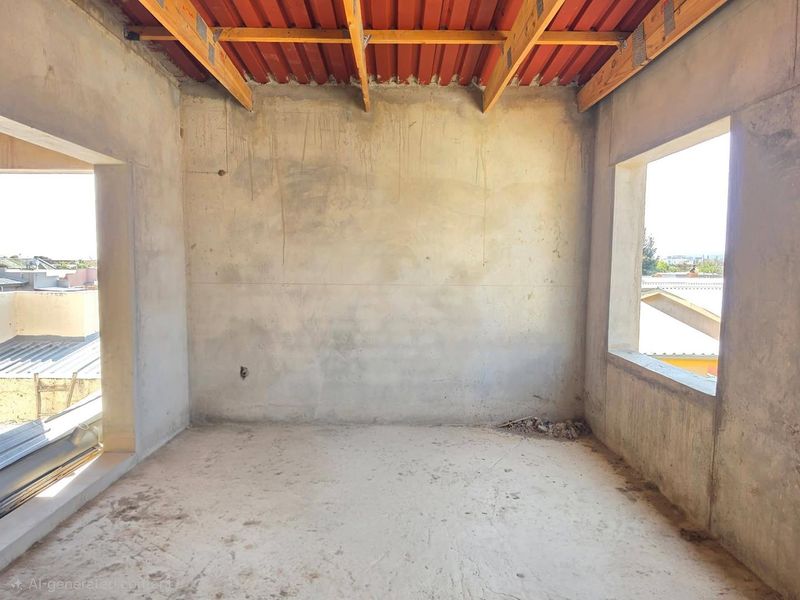 An unfinished bedroom space in shell condition featuring exposed timber roof trusses, concrete walls, and flooring, offering a blank canvas for custom interior finishes.