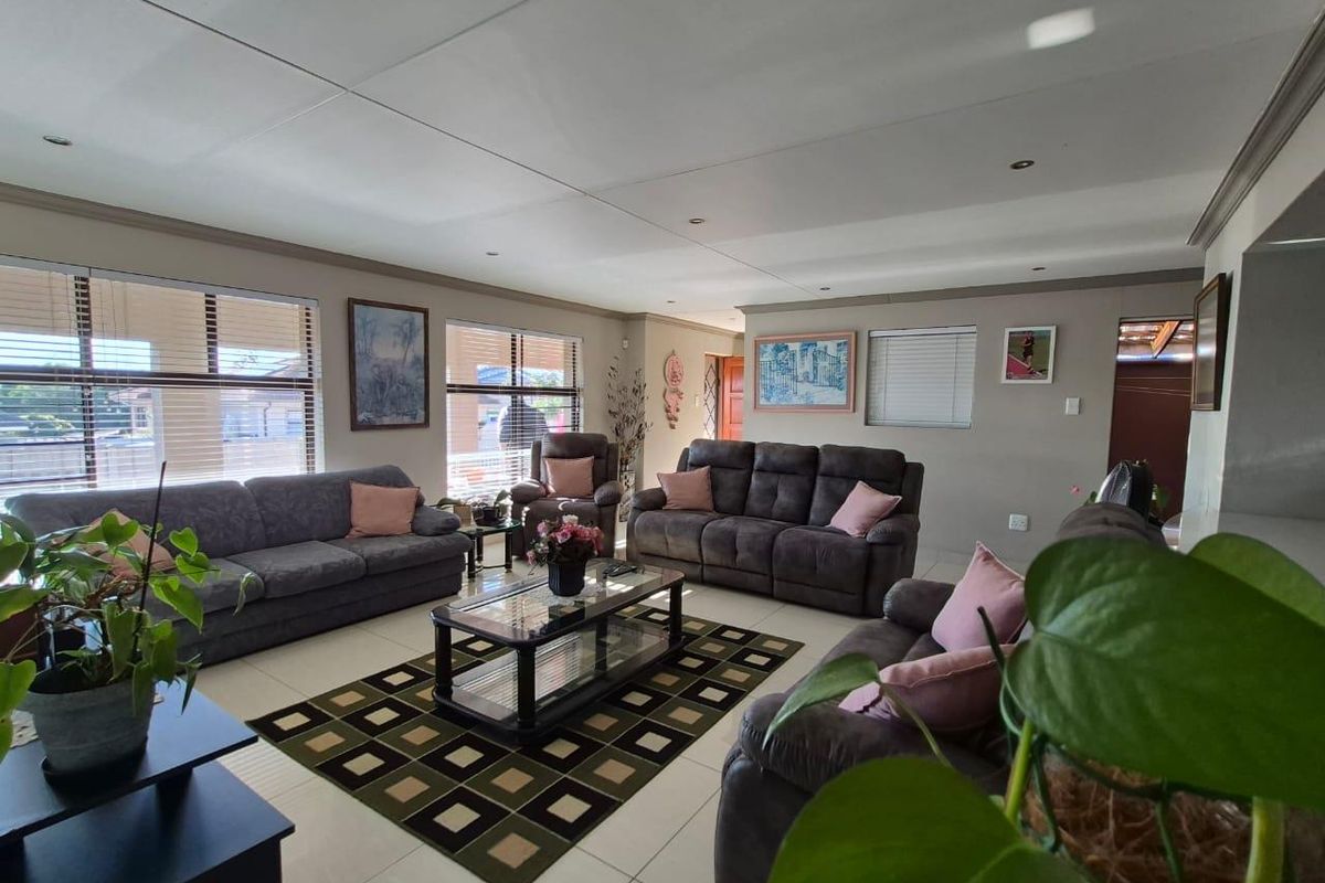 Spacious living room featuring neutral tiled flooring, recessed ceiling lighting, and large windows with fitted blinds, offering a comfortable and well-lit family area.