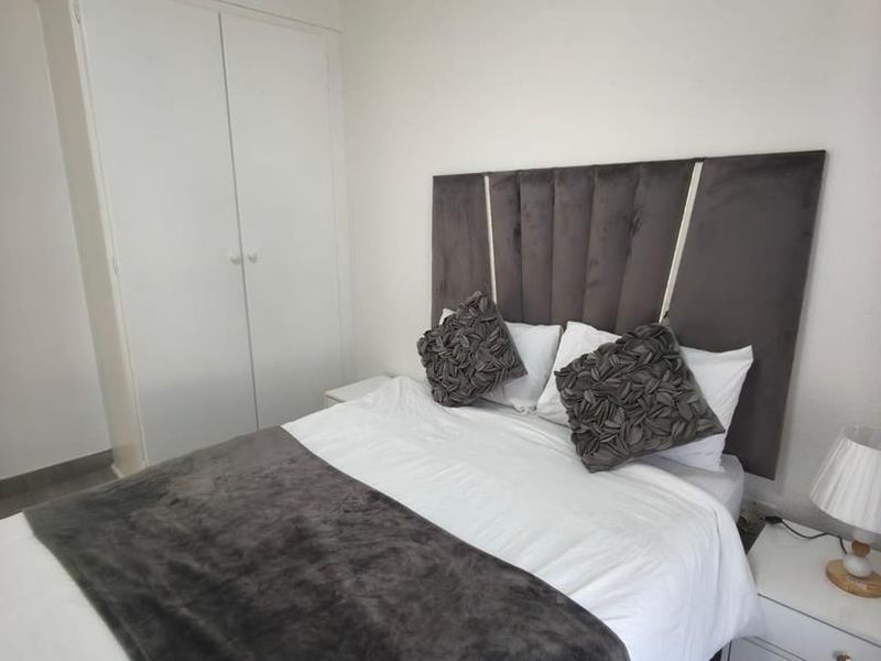 A clean and well-maintained bedroom featuring neutral walls, tiled flooring, and a functional built-in wardrobe.