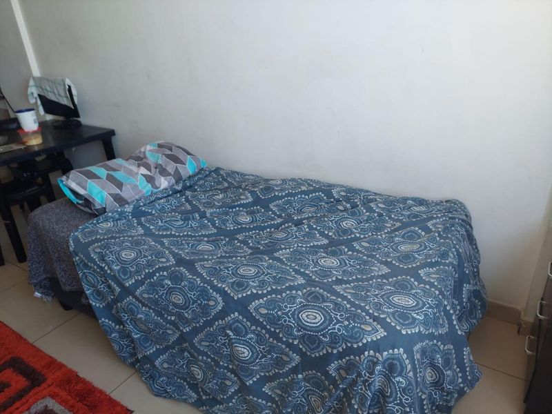 A simple bedroom space featuring tiled flooring and neutral wall finishes.