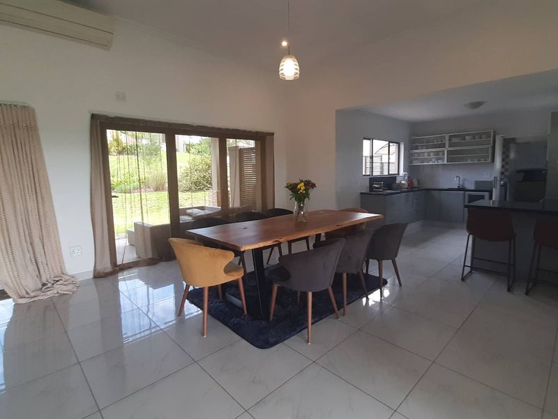Open-plan living and dining area featuring tiled floors, sliding doors to the garden, and a modern kitchen with an island and ample cabinetry.