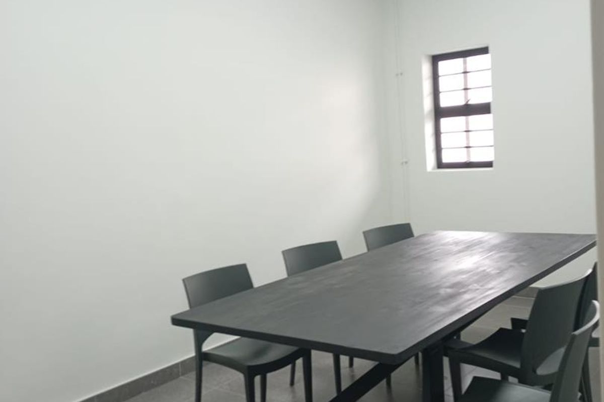 A clean, functional office space featuring tiled flooring, recessed ceiling lighting, and a security-barred window, suitable for professional use.