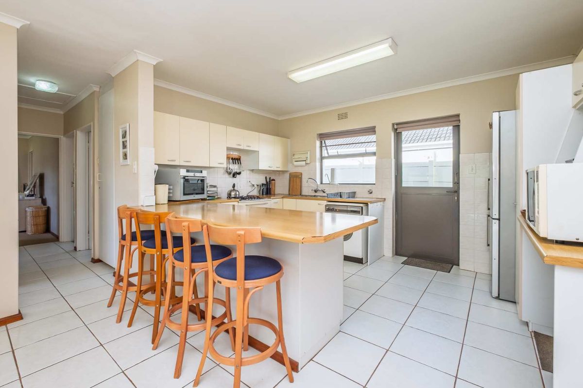 Functional kitchen featuring a breakfast bar, tiled flooring, built-in cabinetry, and direct access to the exterior.