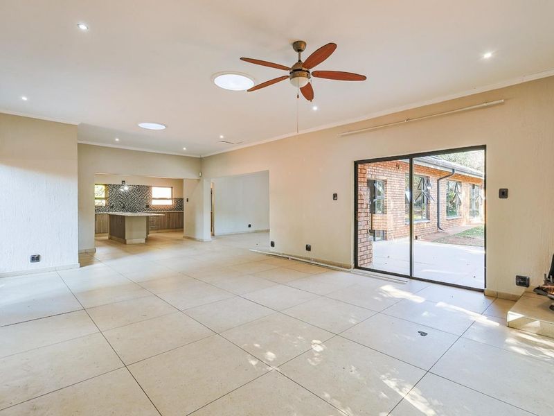 Spacious open-plan living area featuring tiled floors, a built-in fireplace, ceiling fan, and direct access to the rear patio through sliding glass doors.