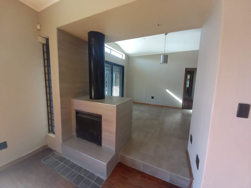 Spacious living area featuring a modern central fireplace, split-level flooring with a combination of tile and wood, and access to outdoor sliding doors.