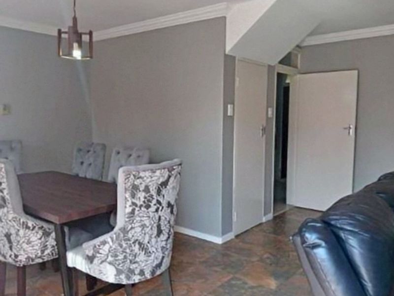 Open plan living and dining area featuring tiled flooring, crown molding, and neutral wall tones, providing a functional space for daily living.