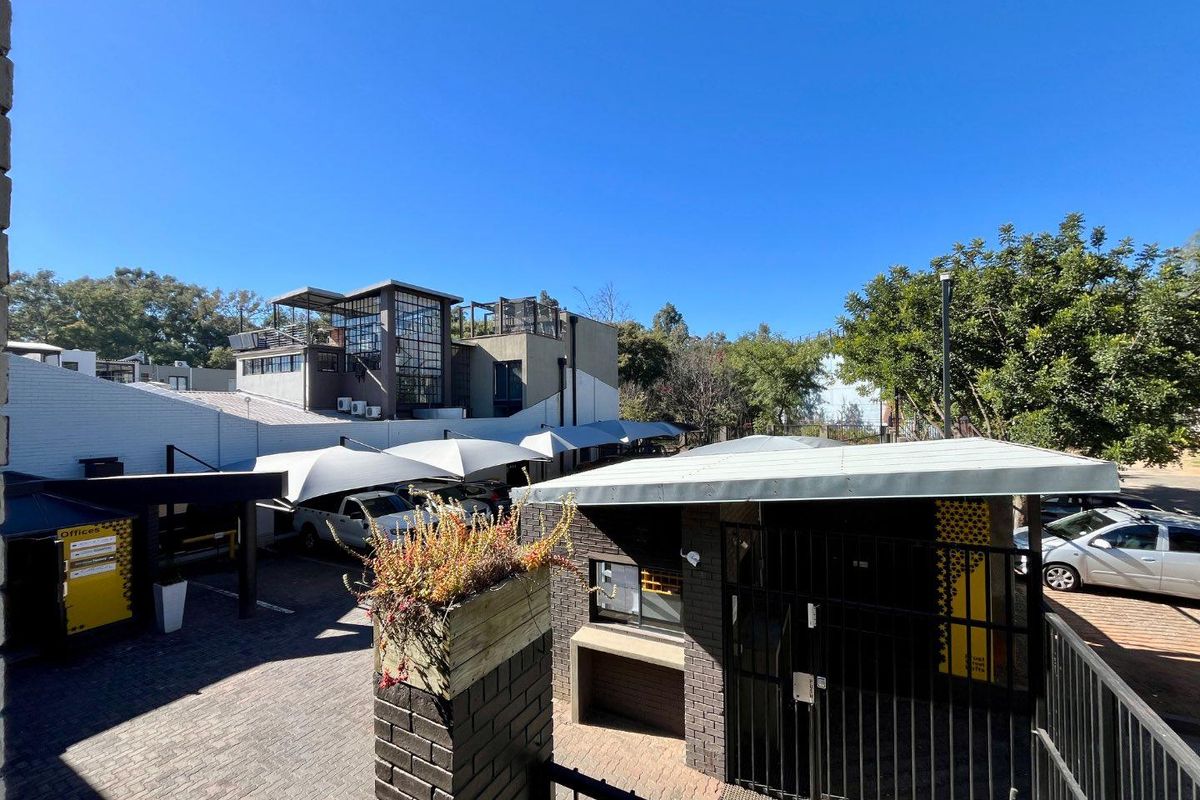 An elevated view of a commercial property exterior featuring paved parking areas, shade sail structures, and a secure gated entrance.