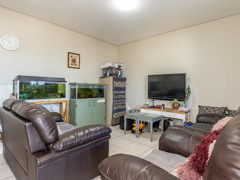 A living room featuring neutral wall paint and tiled flooring, providing a functional space for relaxation.