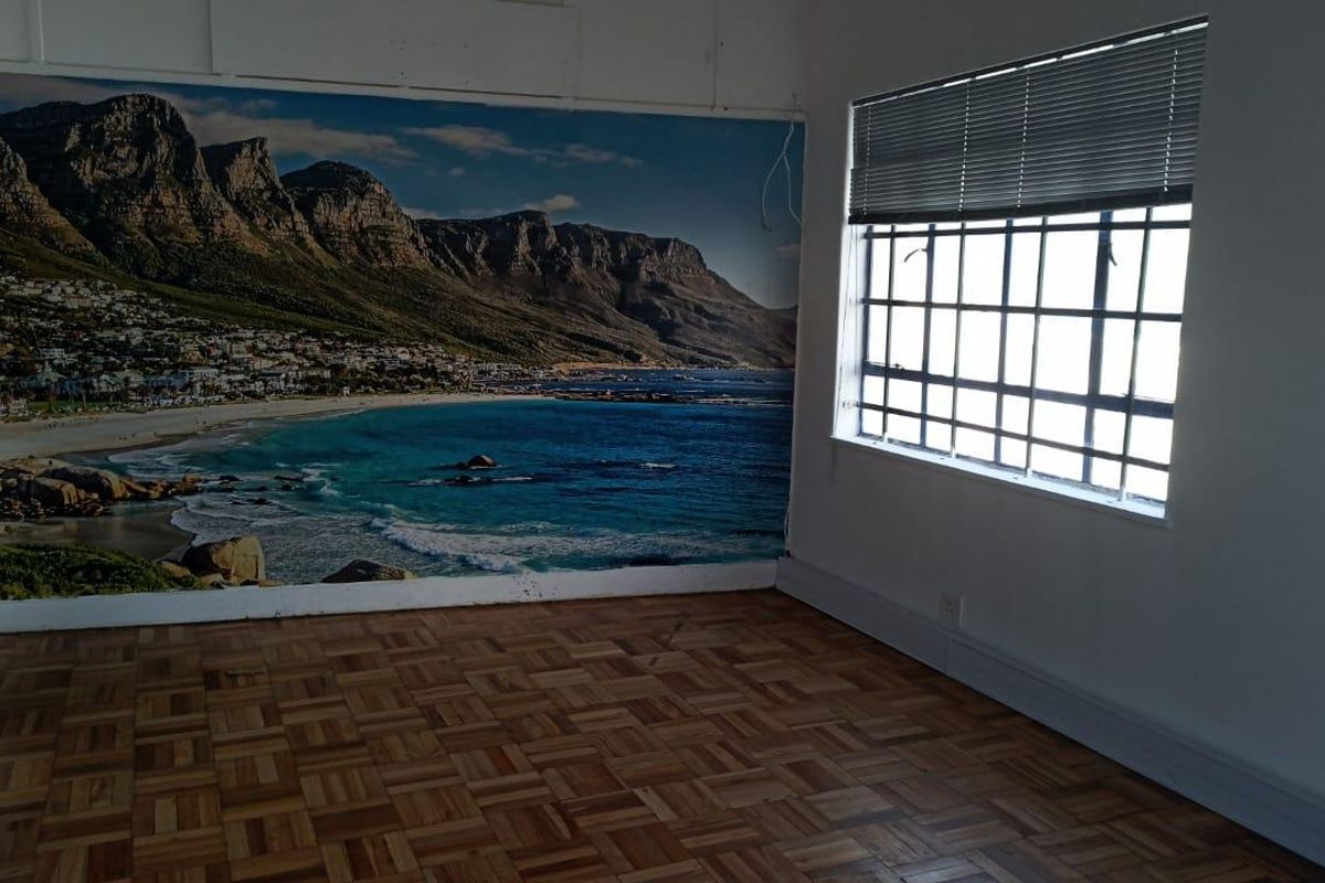 An empty bedroom featuring parquet flooring, security bars on the window, and a large wall mural.