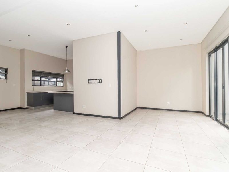 Spacious open-plan living and kitchen area featuring modern tiled flooring, recessed lighting, and large sliding glass doors leading to the exterior.