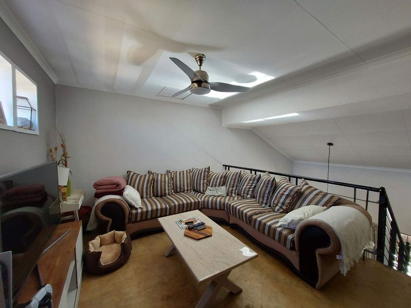 A cozy loft-style living area featuring a sloped ceiling, a skylight for natural light, and a metal safety balustrade overlooking the lower level.