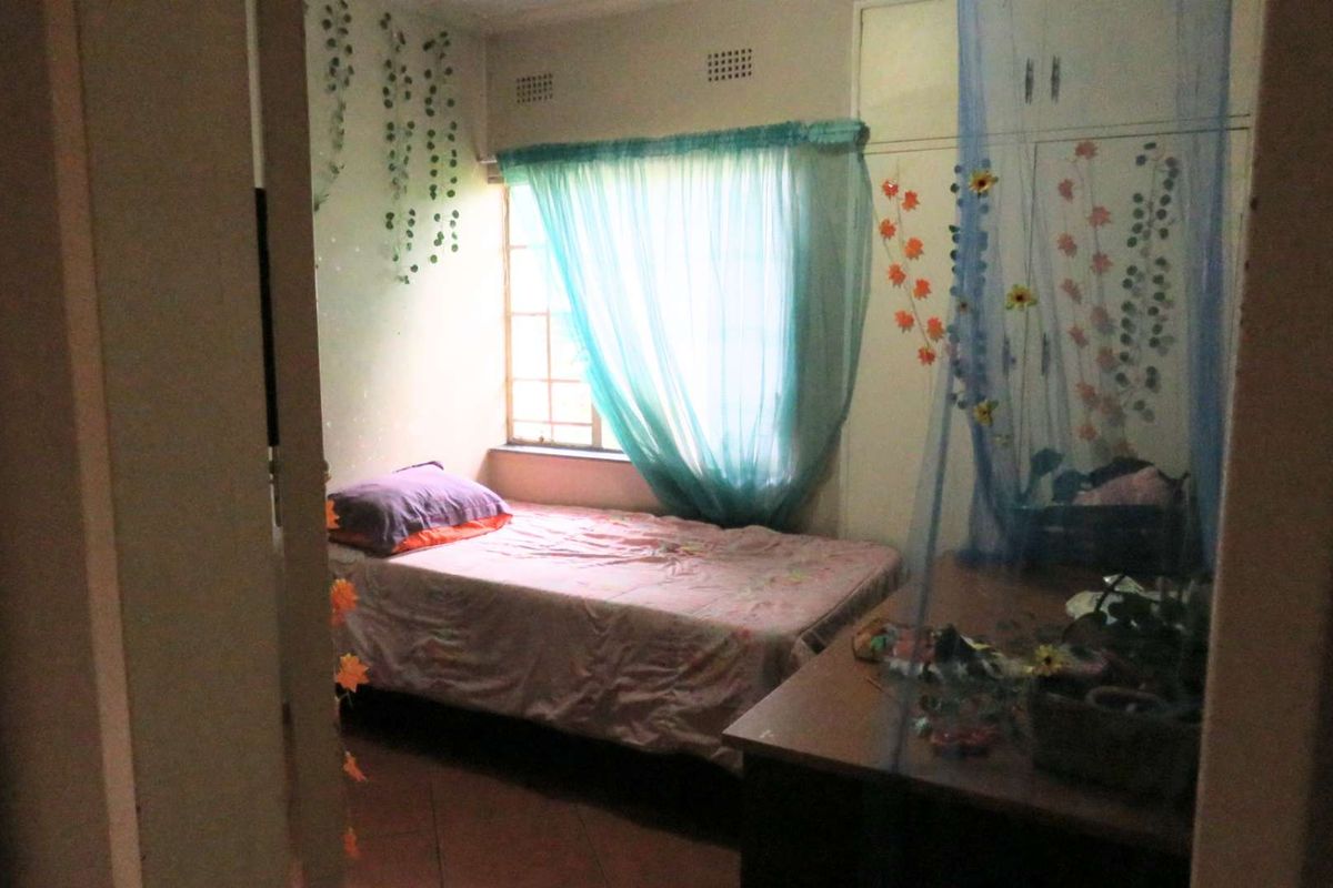 A bedroom featuring built-in cupboards and a window with natural light, providing a functional living space.