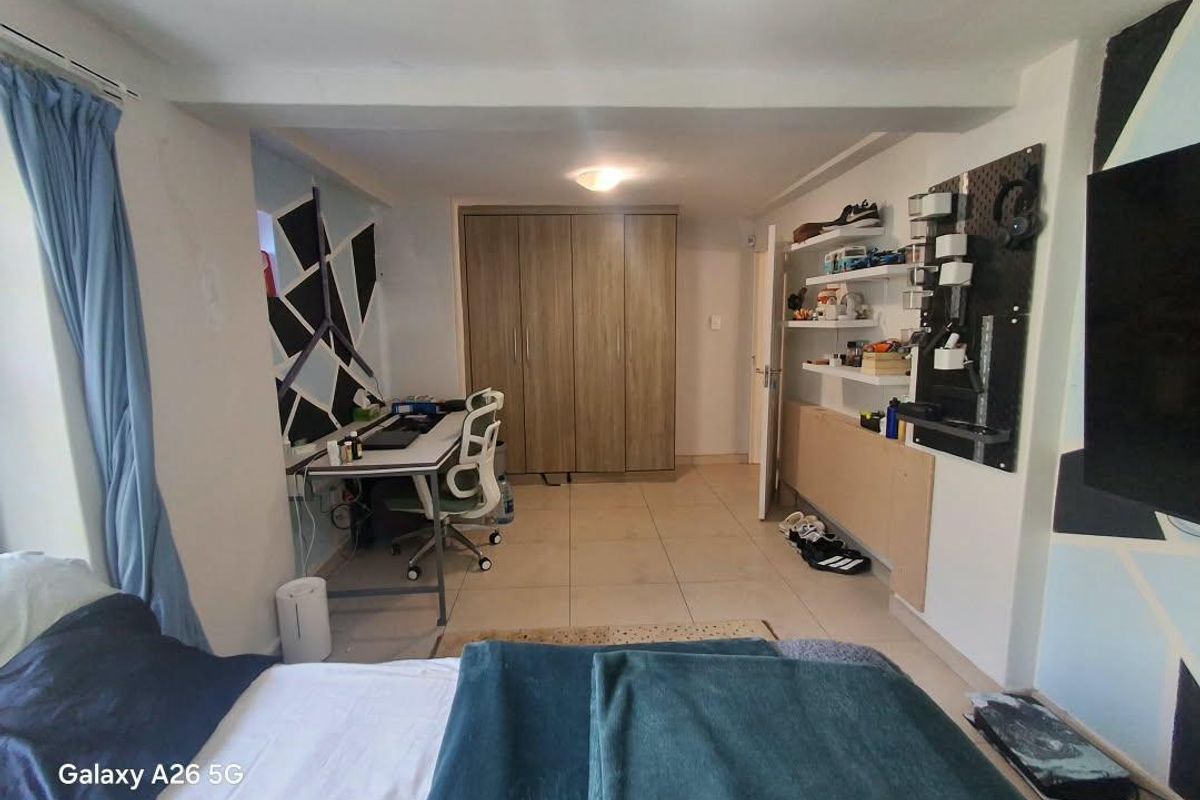 A bedroom featuring built-in wooden cupboards, tiled flooring, and wall-mounted shelving units, providing functional storage and workspace.