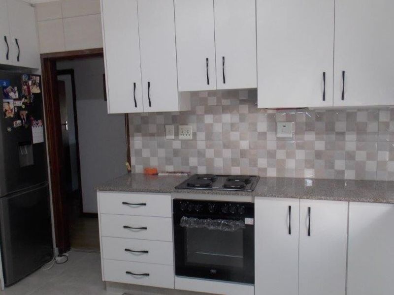 Modern kitchen featuring white cabinetry, granite countertops, a tiled backsplash, and integrated oven and hob.