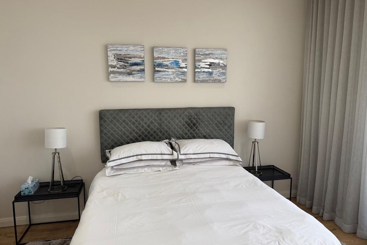 A well-maintained bedroom featuring neutral wall tones, laminate flooring, and floor-to-ceiling curtains, providing a clean and comfortable living space.