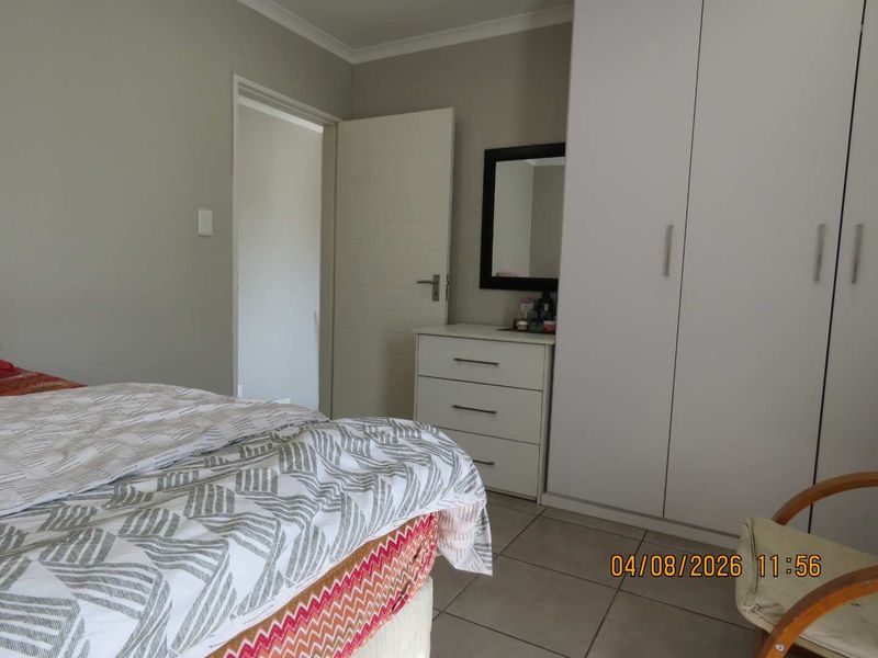 A bedroom featuring built-in cupboards and neutral tiled flooring, offering a clean and functional space.