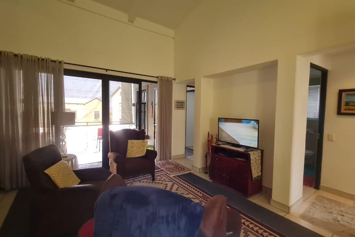 Spacious living area featuring high vaulted ceilings, large sliding glass doors leading to a balcony, and neutral wall finishes.