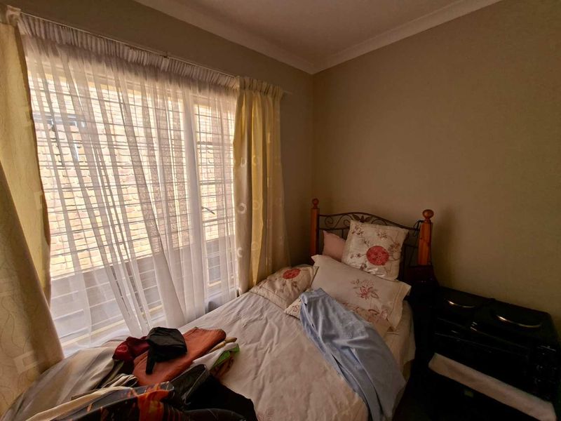 A compact bedroom featuring neutral wall tones, a window with security bars, and classic cove cornicing.