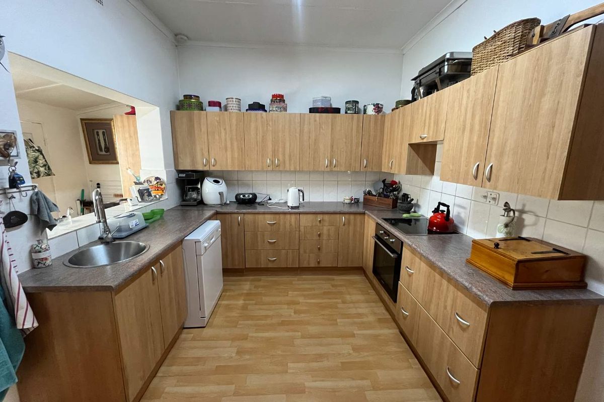 A functional U-shaped kitchen featuring wood-look cabinetry, laminate countertops, a built-in oven, and a ceramic hob with an integrated sink.