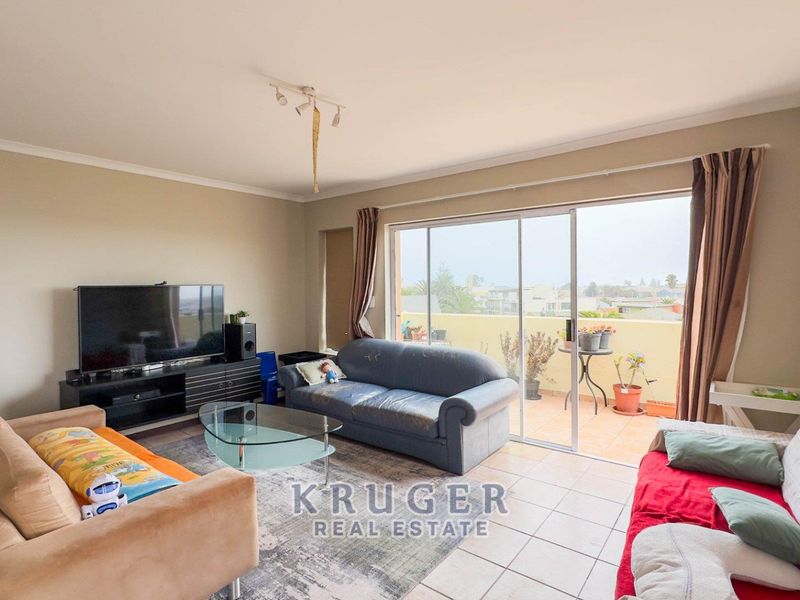 Spacious living room featuring tiled flooring and large sliding glass doors that provide access to an outdoor balcony area.