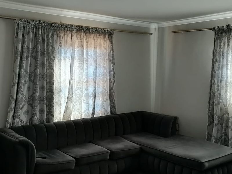 A living room featuring neutral walls, cornicing, and dual window treatments with curtain rods.