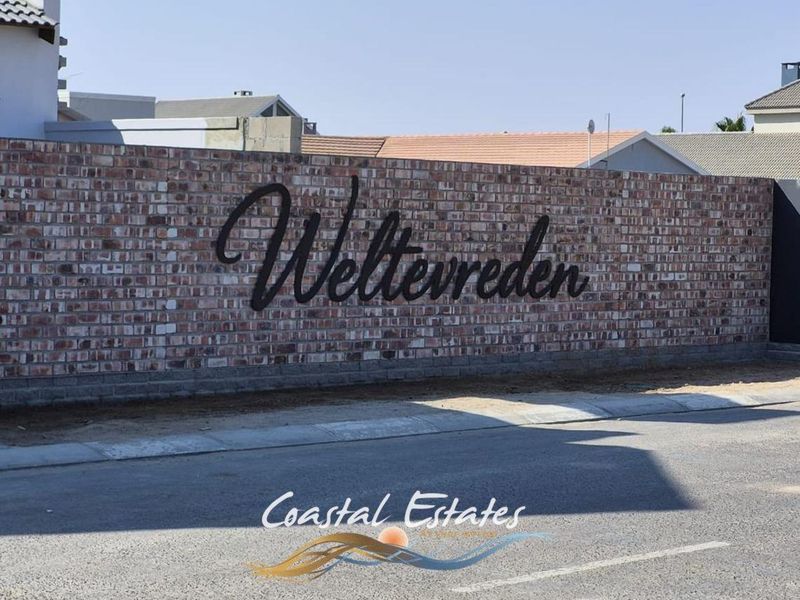 A view of the Weltevreden estate entrance featuring a prominent brick boundary wall with mounted metal signage.