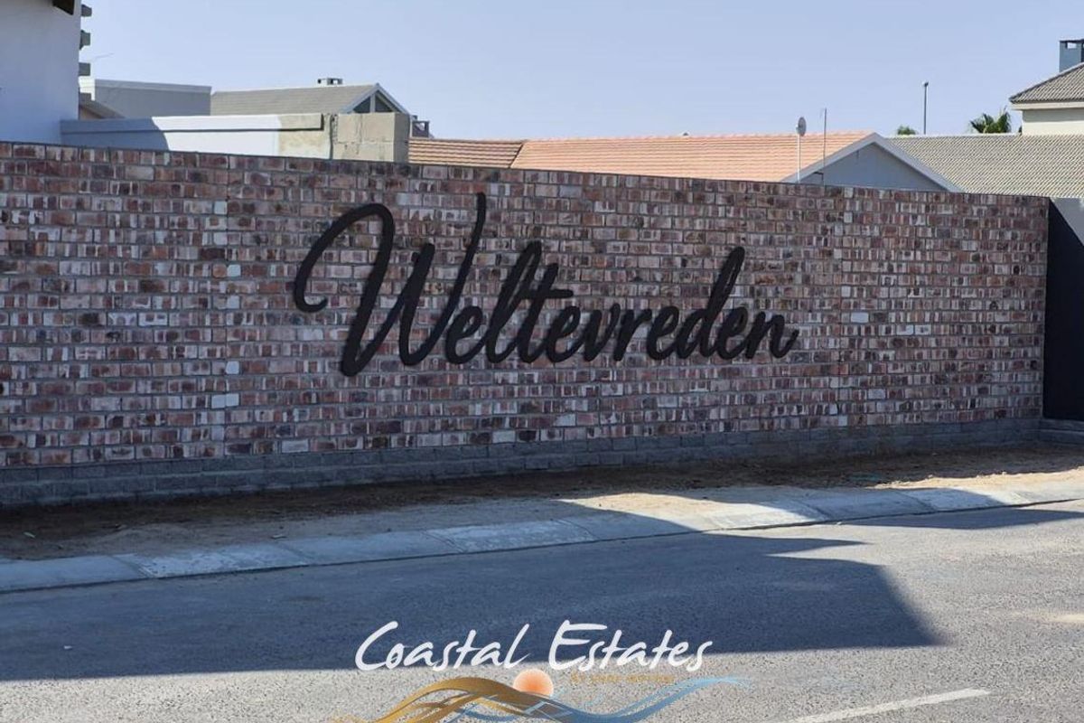 A view of the Weltevreden estate entrance featuring a prominent brick boundary wall with mounted metal signage.