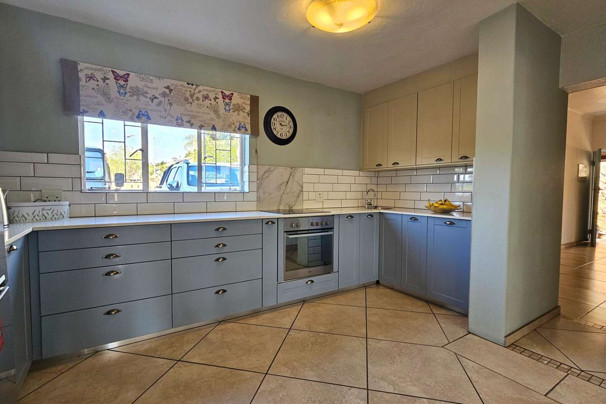 A functional kitchen featuring blue and cream cabinetry, white subway tile backsplash, built-in oven, and tiled flooring.