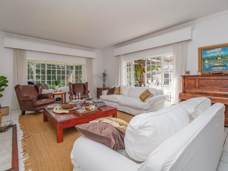 Spacious living room featuring large grid-pane windows, classic crown molding, and direct access to the outdoor area through french doors.