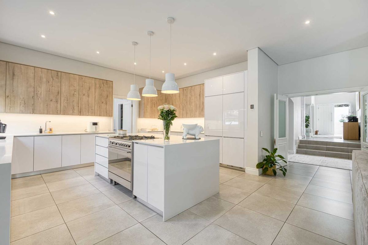 Modern kitchen featuring a central island with a built-in gas cooktop, sleek cabinetry, and integrated appliances, finished with neutral floor tiles.