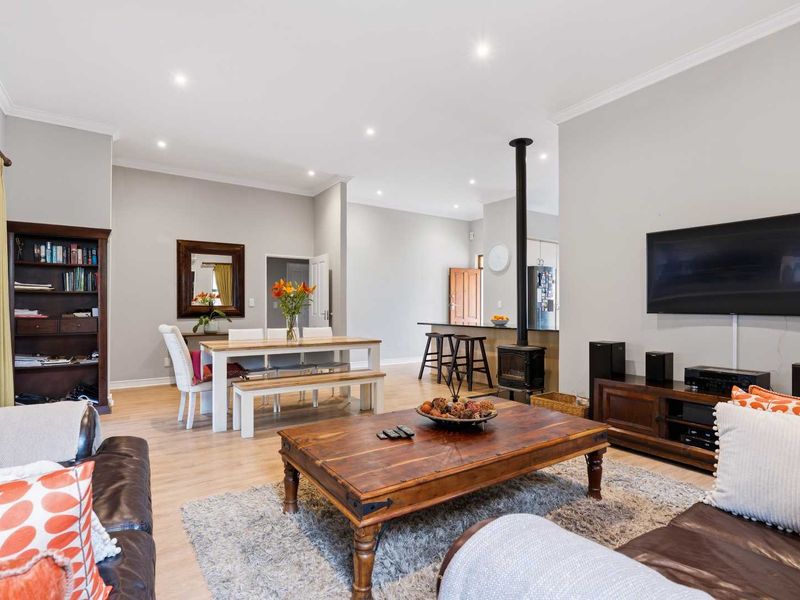 Spacious open-plan living and dining area featuring laminate flooring, recessed lighting, and a central wood-burning fireplace, seamlessly connecting to the kitchen.