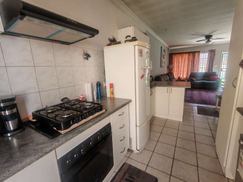 Open-plan kitchen and living area featuring tiled flooring, built-in oven with gas hob, extractor fan, and direct access to the living space.