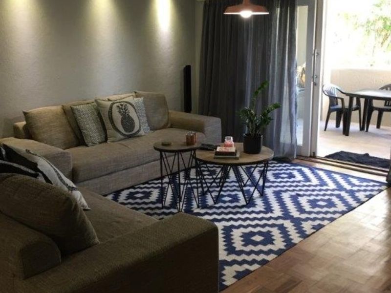 A comfortable living room featuring warm parquet flooring, recessed ceiling lighting, and direct access to an outdoor patio through sliding glass doors.