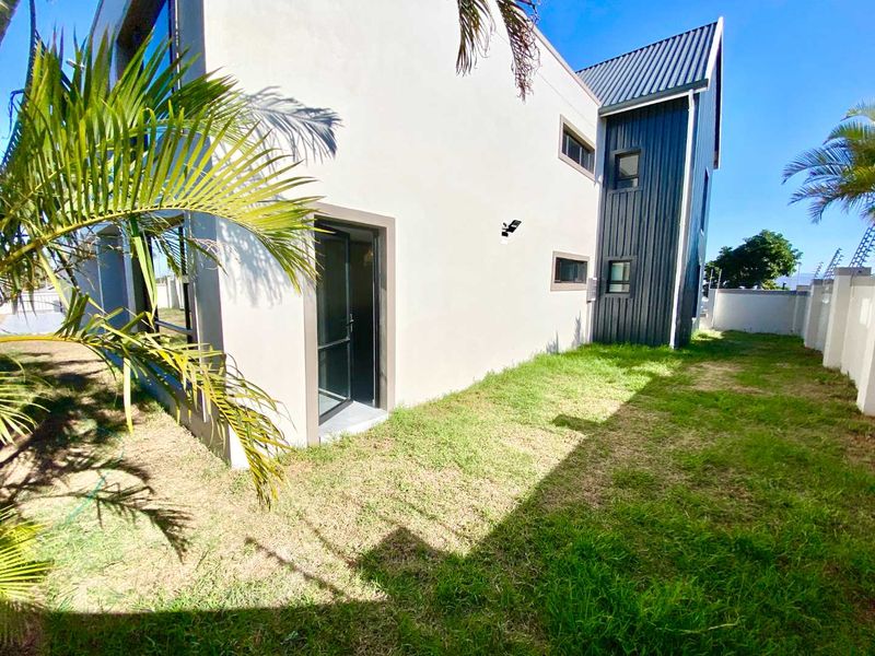 Rear view of the apartment building featuring a combination of plastered walls and dark metal cladding with a private garden area.