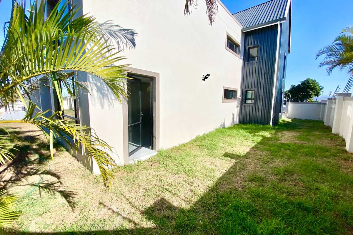 Rear view of the apartment building featuring a combination of plastered walls and dark metal cladding with a private garden area.