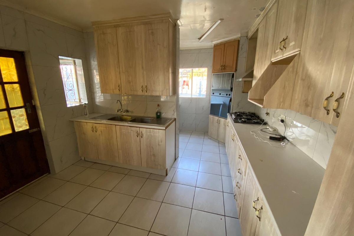 A functional kitchen featuring light wood-look cabinetry, tiled walls and flooring, built-in oven, and gas hob, offering a blank canvas for modern updates.